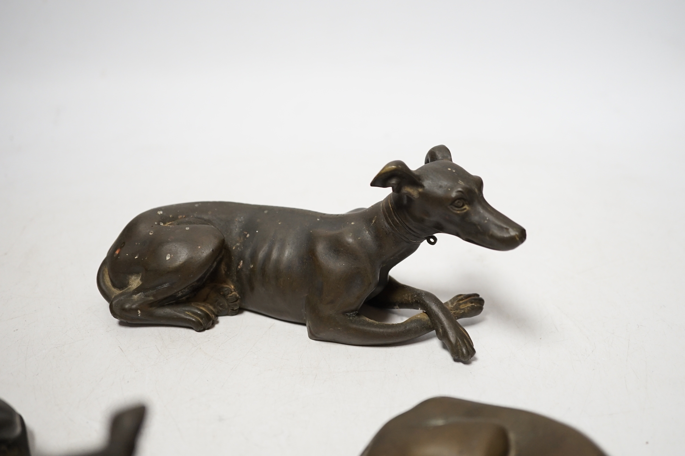 Three late 19th century bronze models of recumbent greyhounds, 17cm